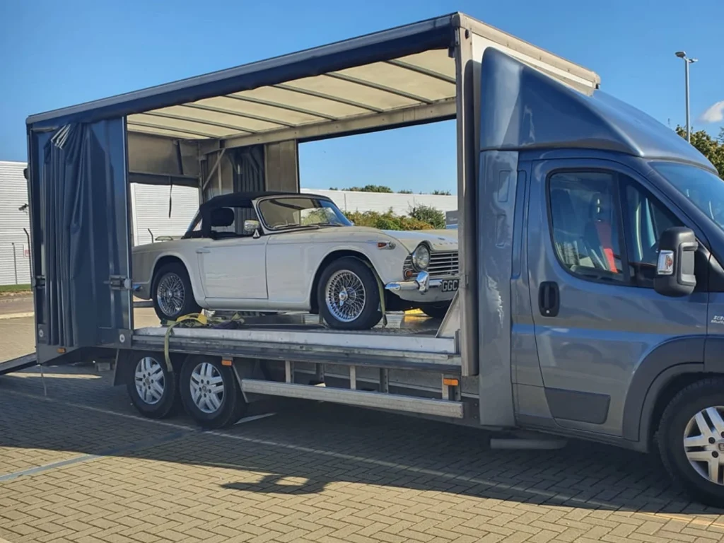 Flatbed truck transporting a car safely during a house move in the UK