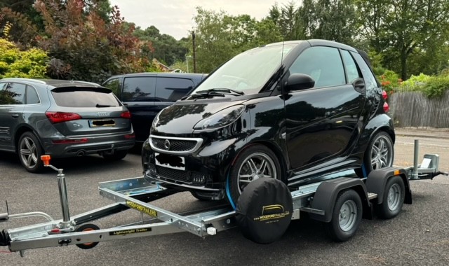 Car being transported on a flatbed truck instead of being driven