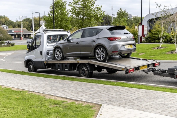 Car being prepared for transport on a flatbed truck in the UK